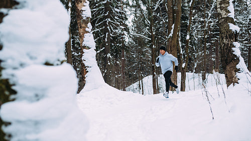 Young healthy man running in forest at winter