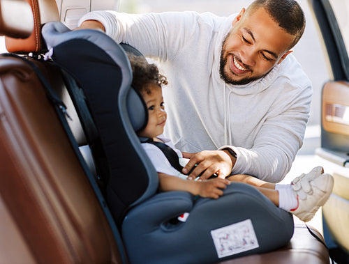 Smiling man looking on his son inside of a car