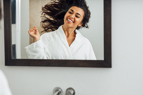 Happy woman enjoying good mood after home spa looking at mirror