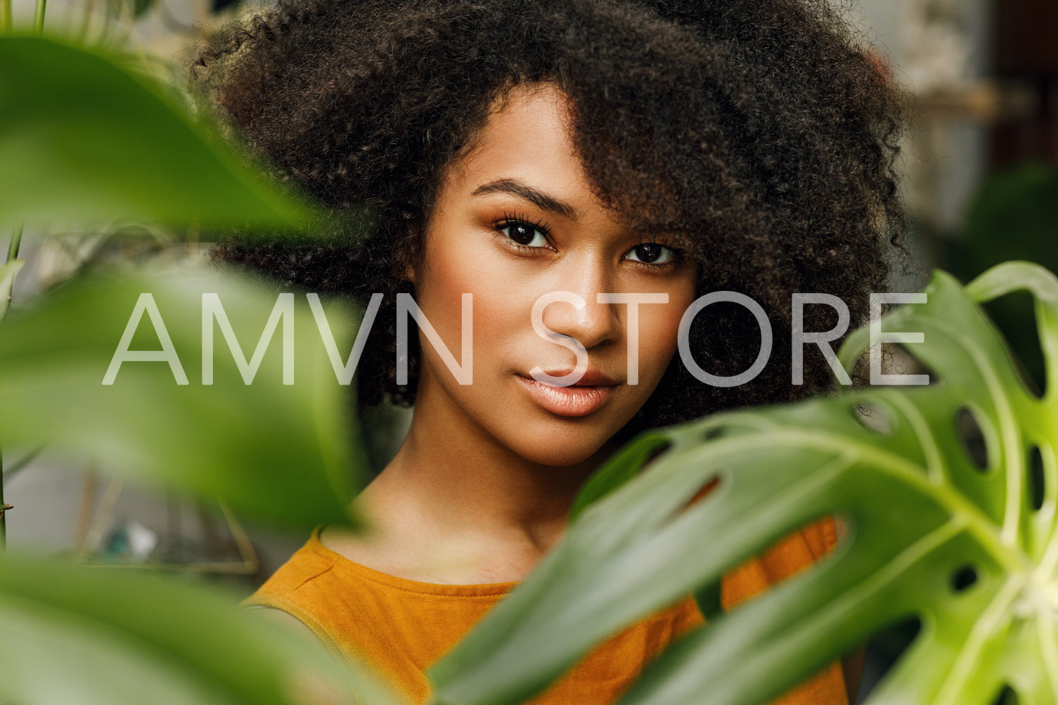 Portrait of a young woman. Beautiful female posing in plant shop near monstera leaves.	