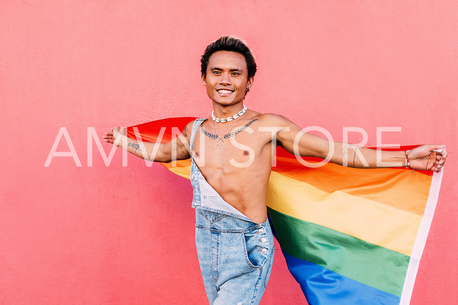 Young happy man walking outdoors with a rainbow LGBT flag looking away