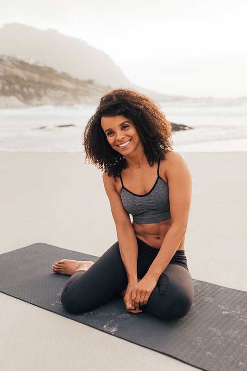 Smiling female on a mat outdoors. Beautiful woman taking a break during training.