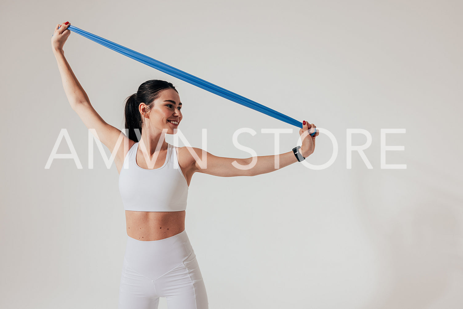 Smiling woman in white fitness attire warming up hands with resistance band