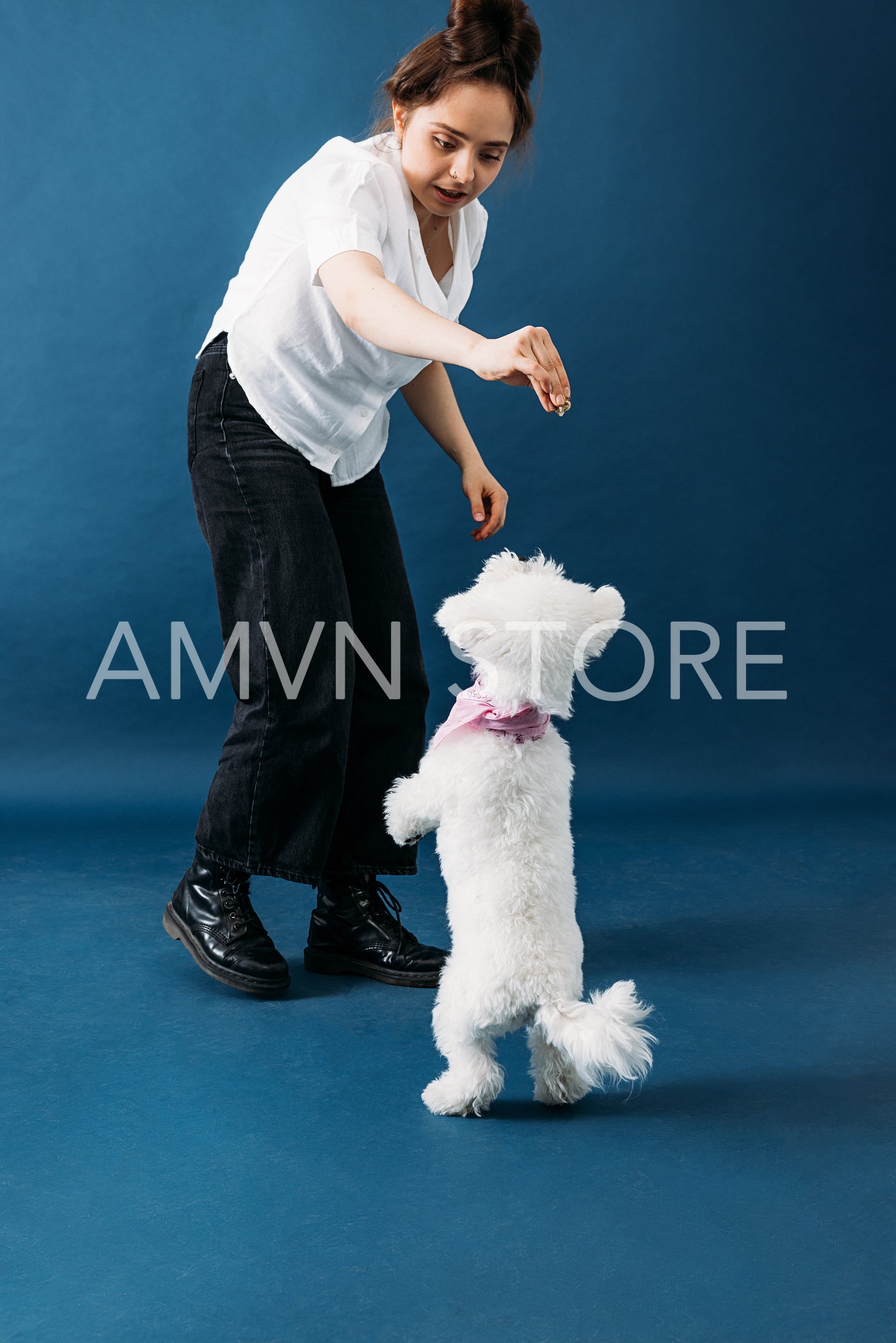 Young woman feeding her little fluffy dog and playing