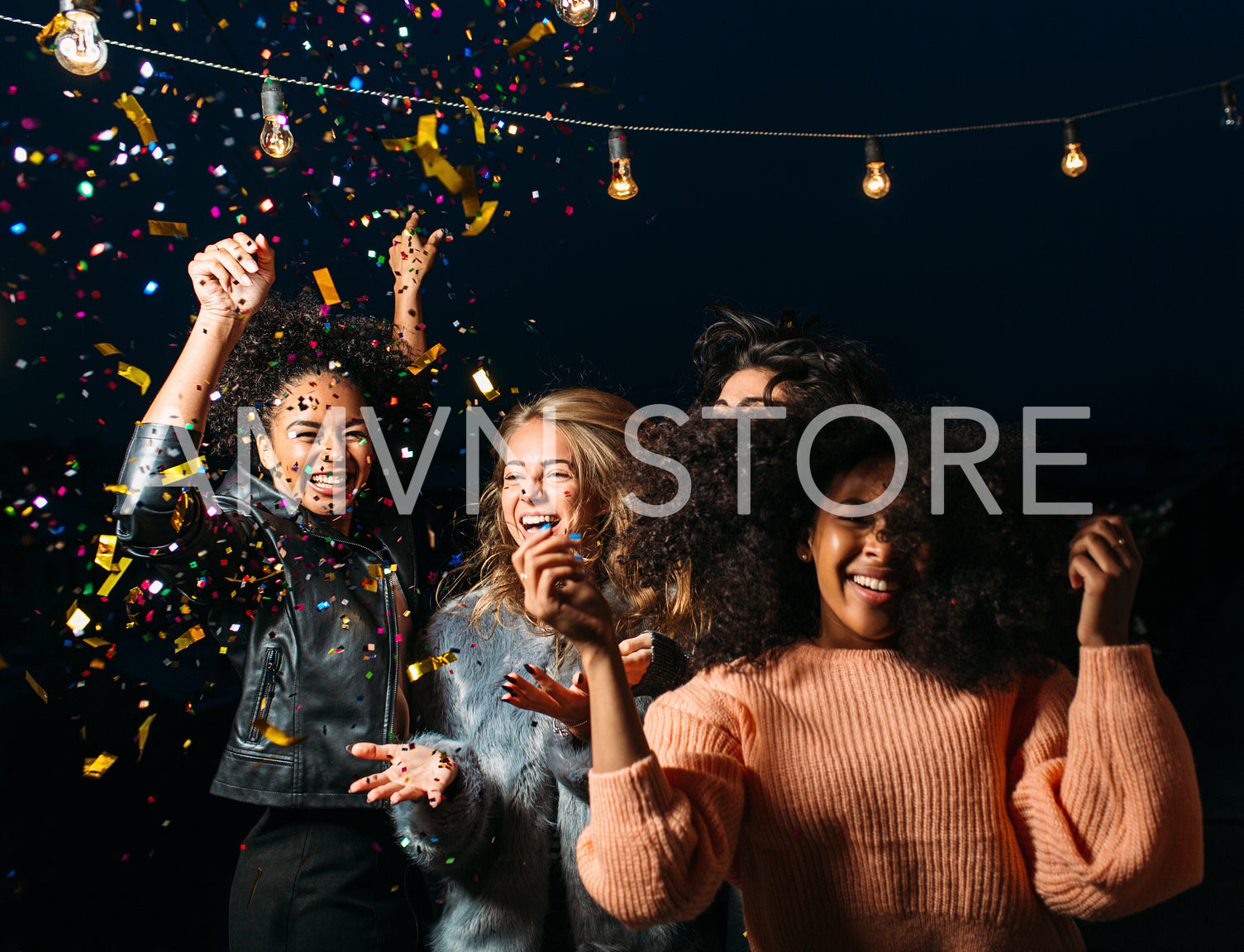 Happy and laughing females dancing at night under confetti