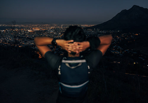 Unrecognizable woman hiker enjoying the view of a night city from mountain