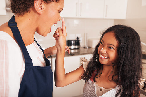 Granddaughter and grandmother having fun together in the kitchen while baking cupcakes