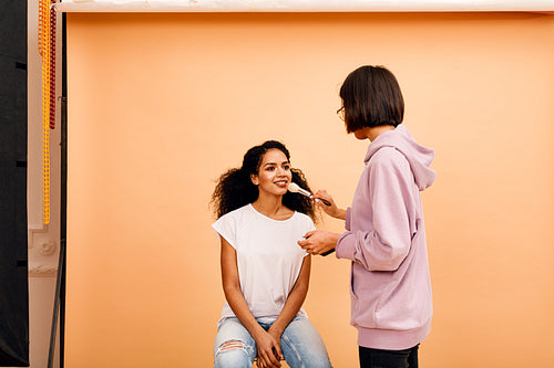 Makeup artist in studio. Two people preparing for photoshoot.