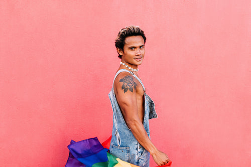 Handsome guy posing outdoors with LGBT flag and looking at camera