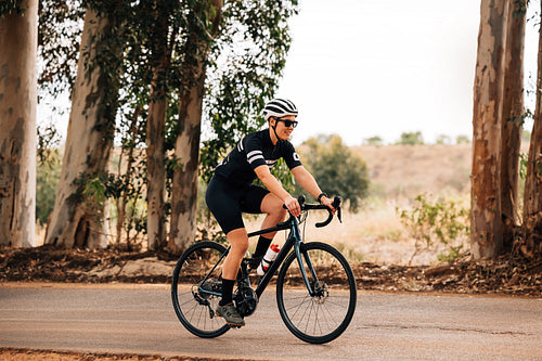 Professional female cyclist in sunglasses and helmet riding bike outdoors