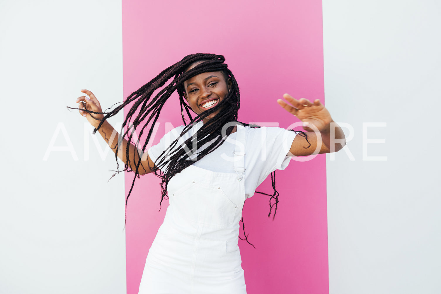 Cheerful girl with long braids enjoying good mood while standing at wall outdoors