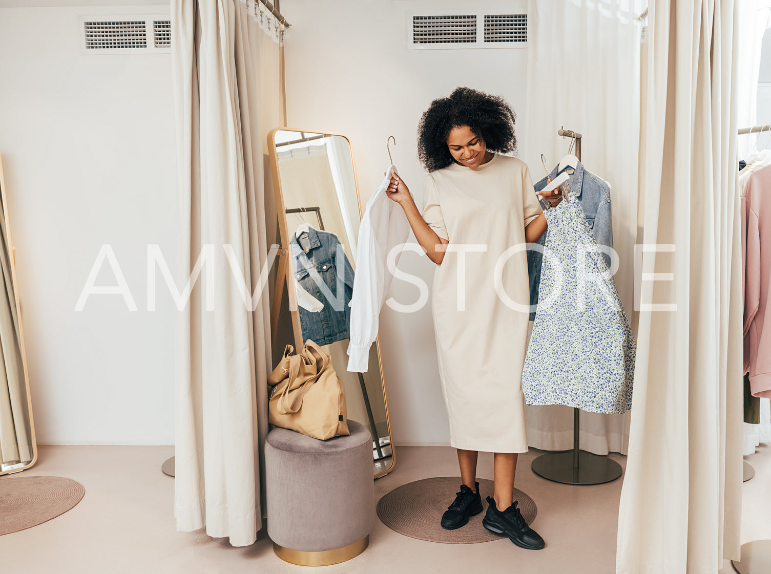 Young stylish woman standing in dressing room showing clothes she choosing