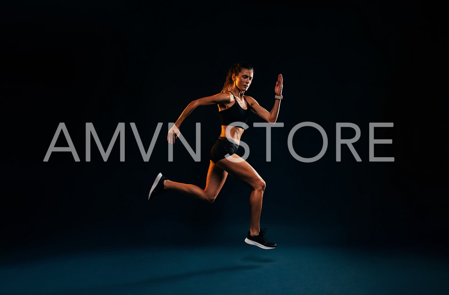 Female runner sprinting on black background. Fit woman jumping w