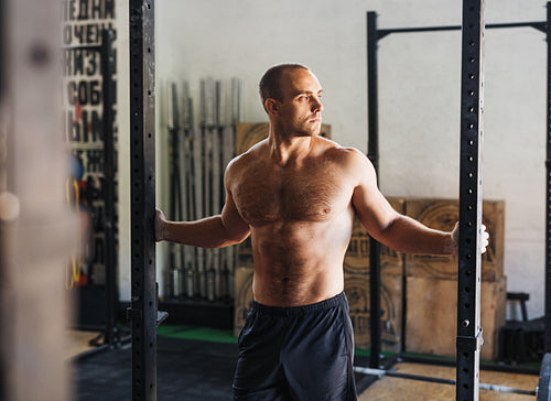 Shot of a muscular athlete standing in sport club, resting during workout