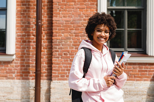 Smiling girl standing at school with books and backpack