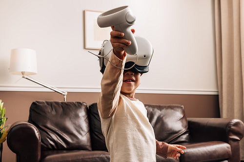 Kid playing virtual reality games at home. Little boy having fun with VR.