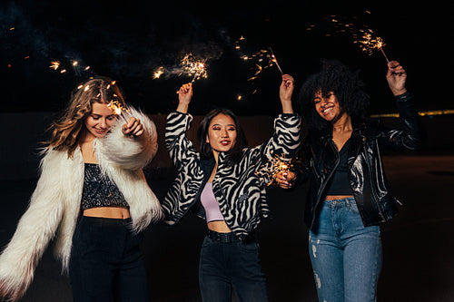 Happy stylish girls walking together at night and having fun