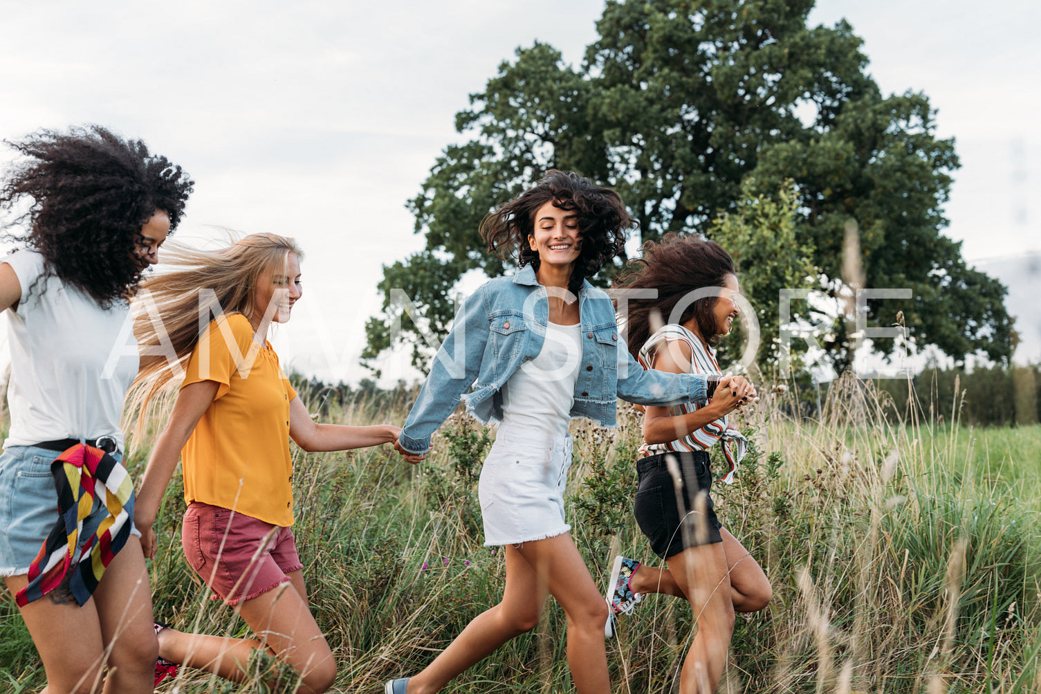 Group of a happy woman running and jumping outdoors. Female friends having fun on a field.