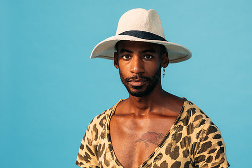 Portrait of African American guy wearing straw hat and looking straight of a camera