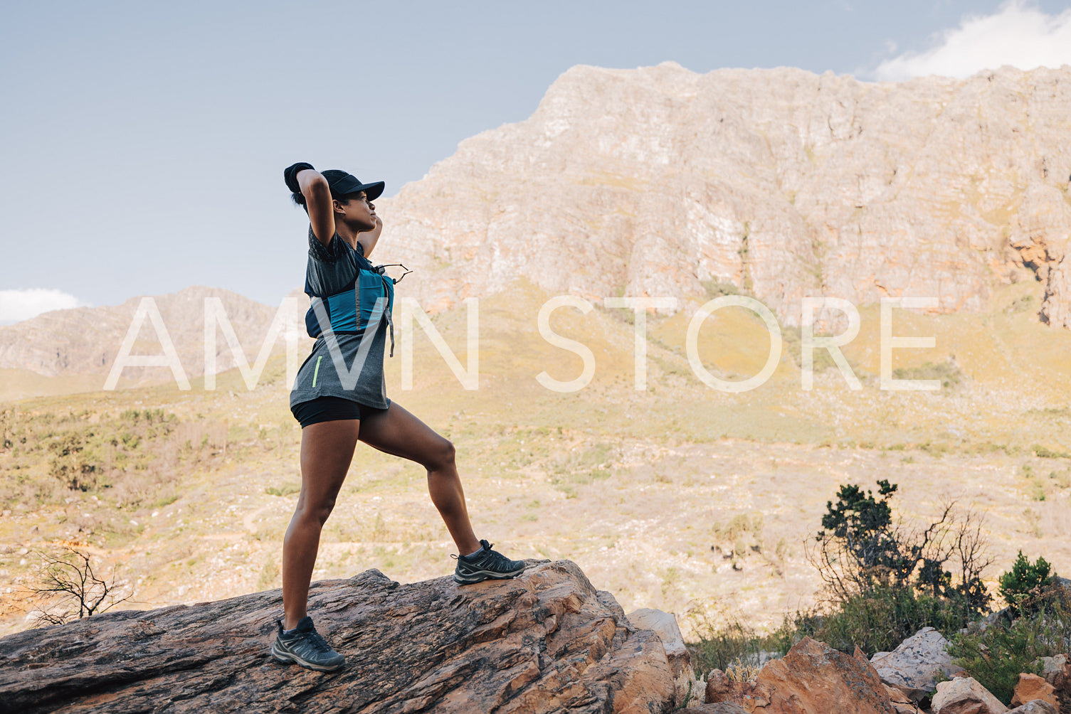 Side view of fit woman standing on a rock enjoying the view agai