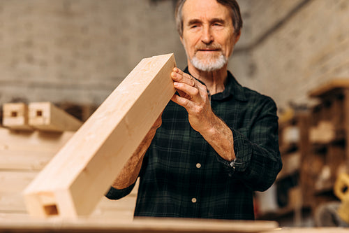 Senior carpenter checking a block of wood indoors