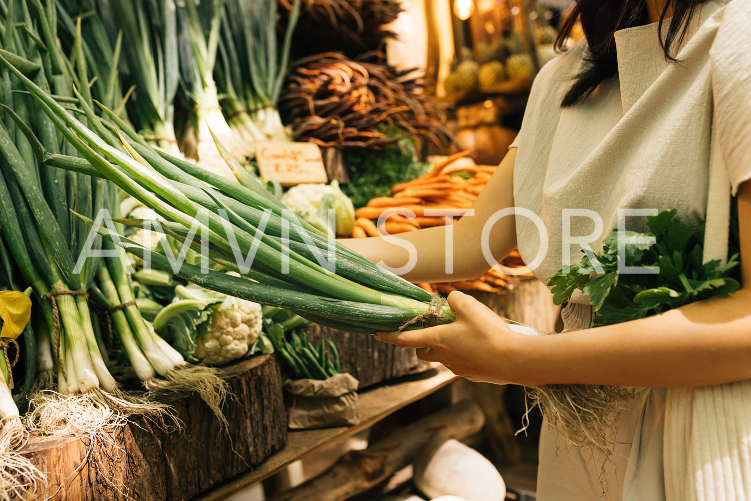 Hands of an unrecognizable woman holding a fresh spring onion at an outdoor market stall