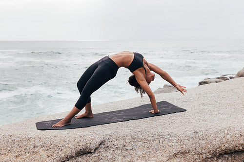 Woman doing Wild Thing yoga pose outdoors. Female practicing Camatkarasana pose at evening.