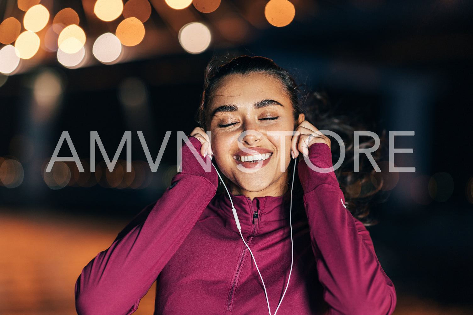 Cheerful woman with closed eyes listening to music during training at night