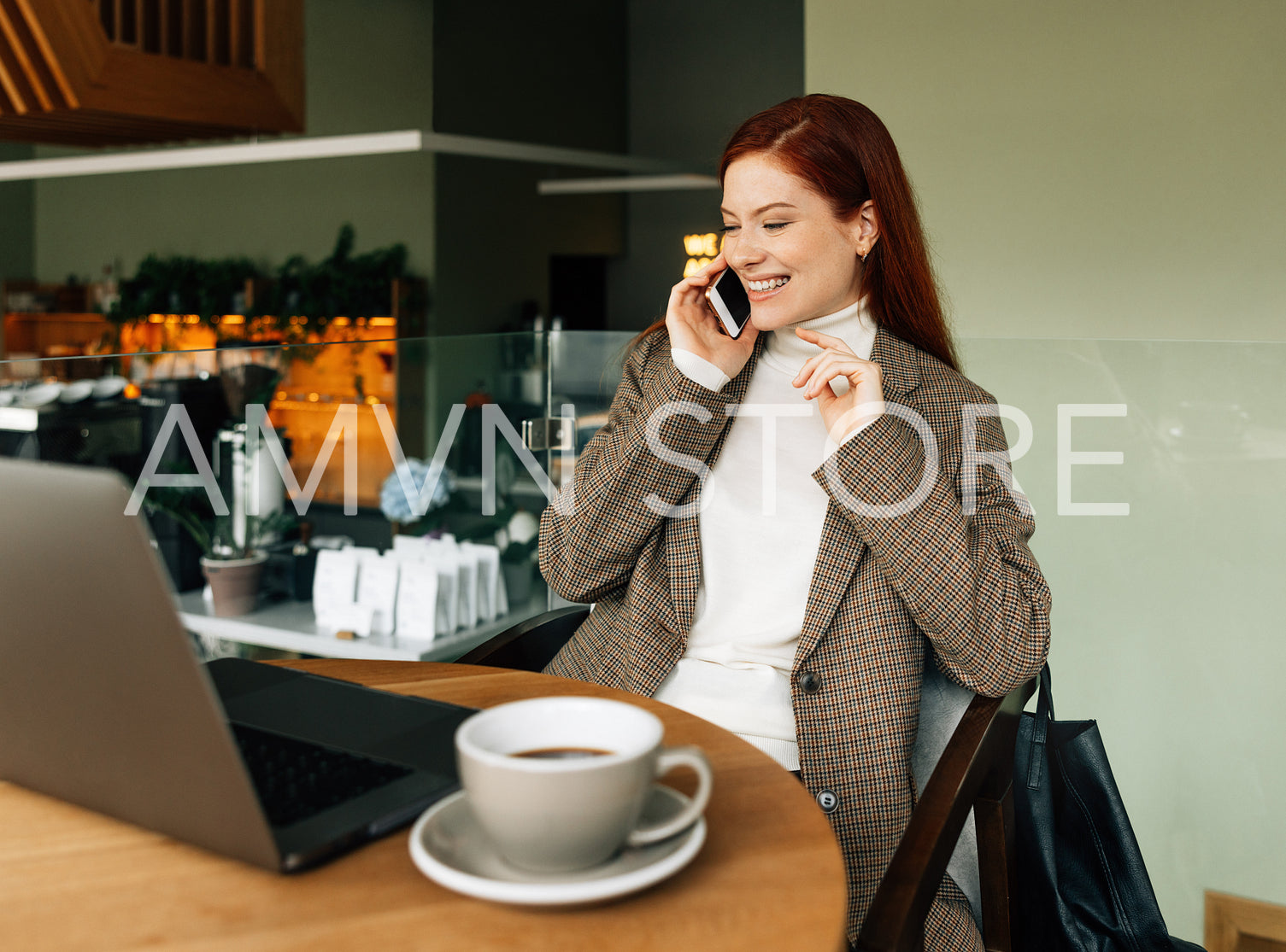 Cheerful redhead female making a call while sitting in a coffee shop