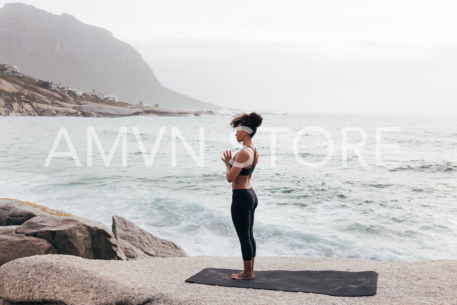 Slim female standing on mat with folded hands. Woman relaxing in praying pose during yoga exercises.