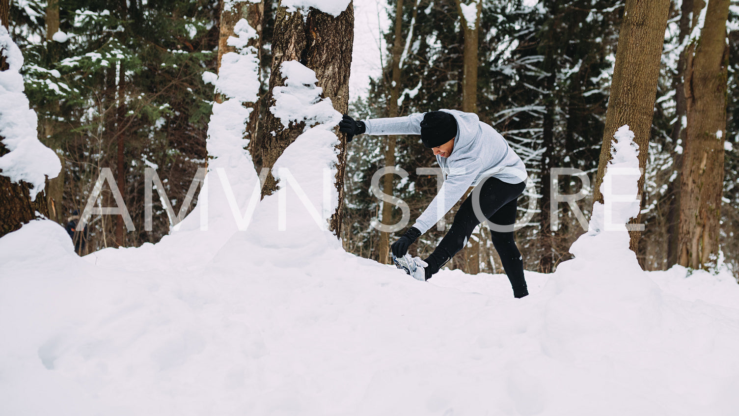 Runner doing stretching exercises in a winter park, warming up before training	
