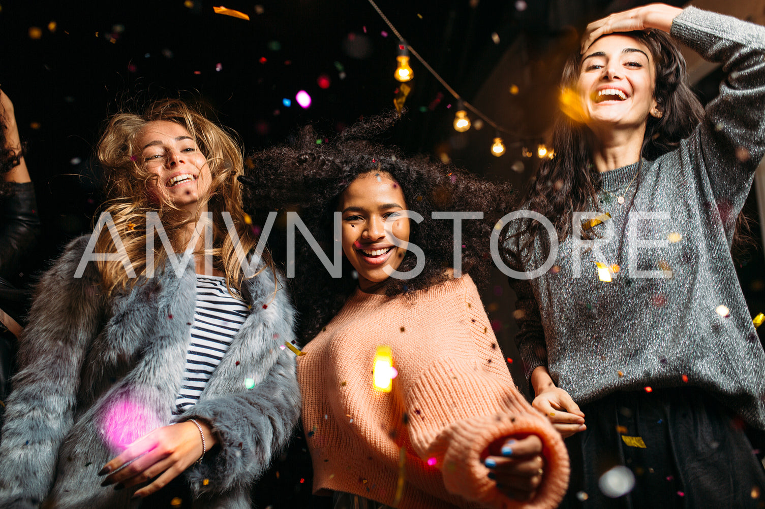 Group of female friends dancing, enjoying roof party with confetti	