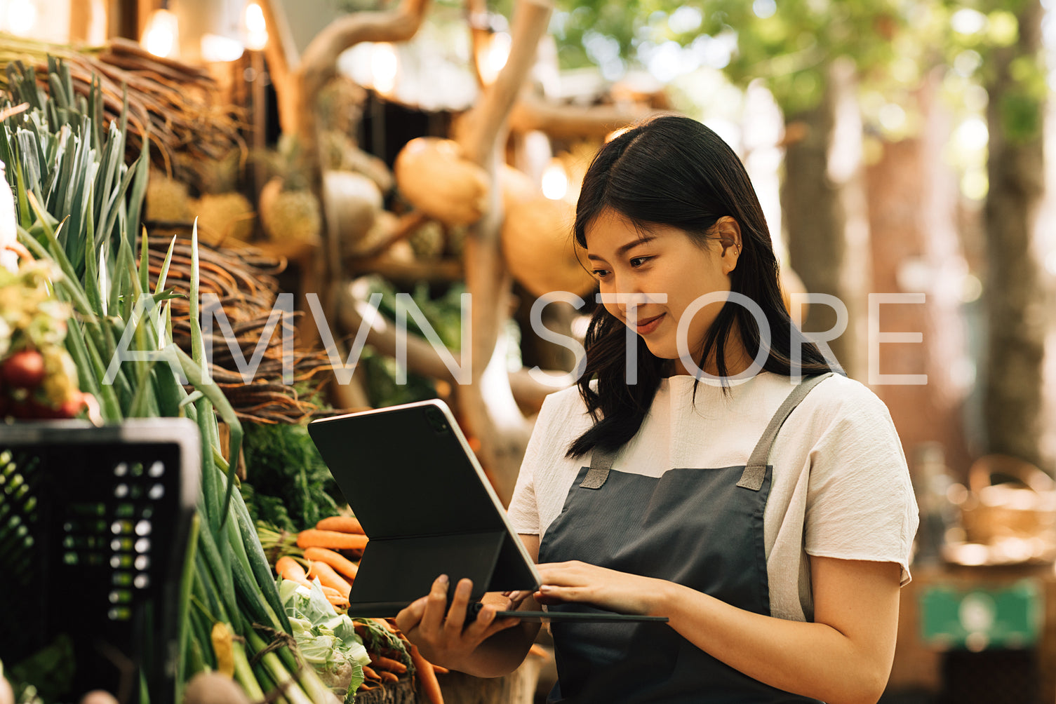 Vendor using digital tablet at an outdoor market stall. Young entrepreneur with a portable computer on the seasonal farmers market.