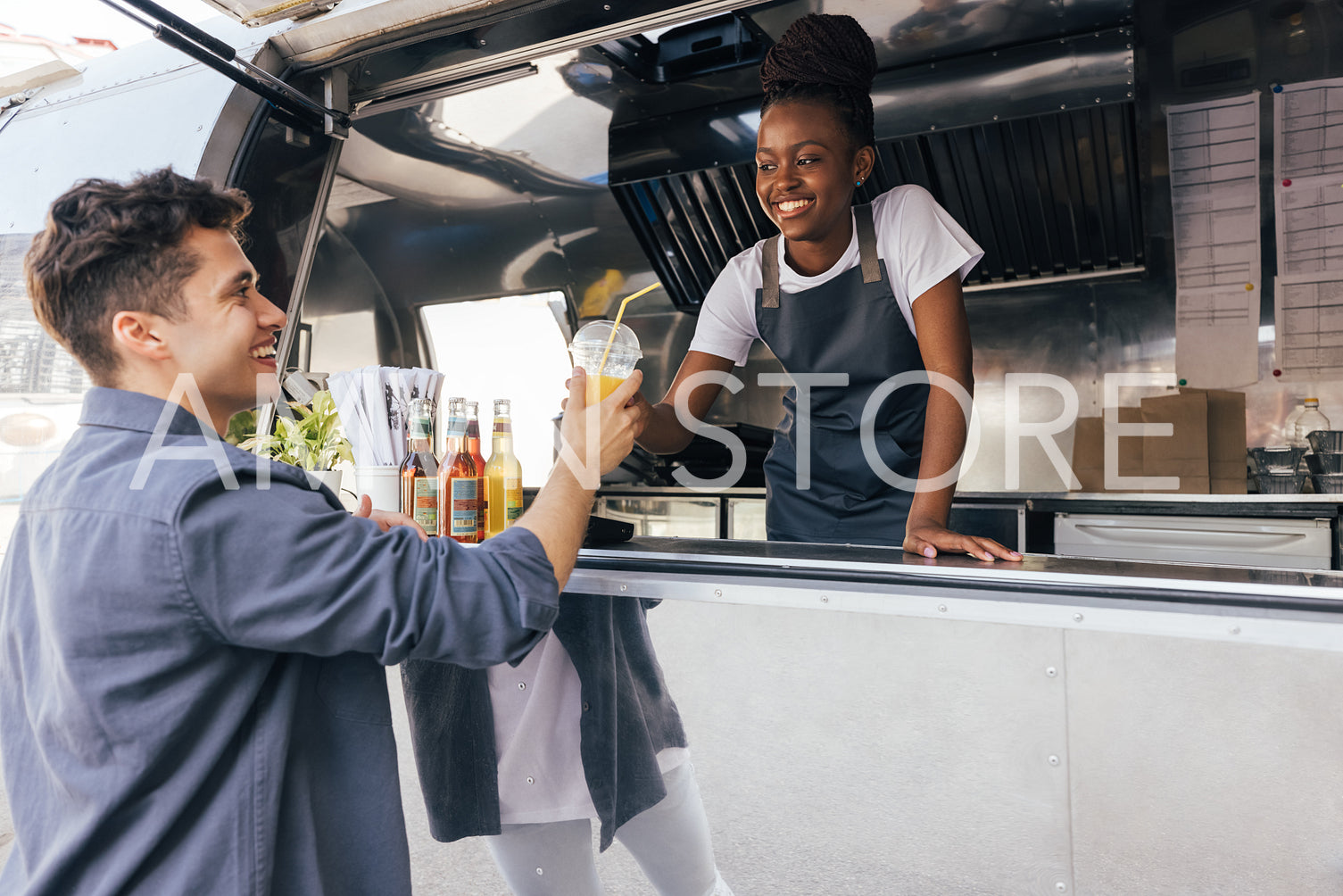 Food truck owner looking at customer. Smiling client receiving a drink from saleswoman.