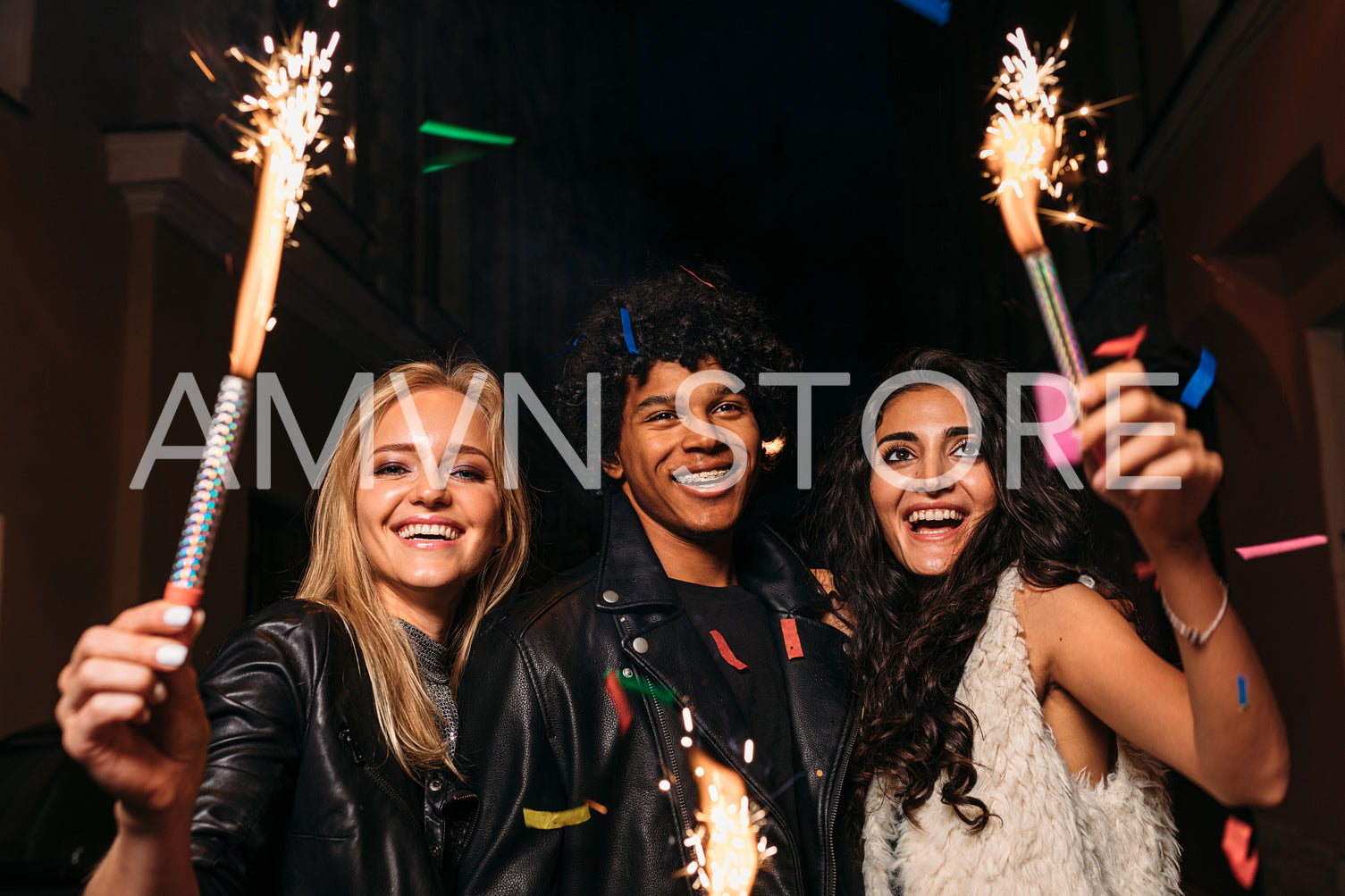 Young man and women having fun at night street with sparklers and confetti	