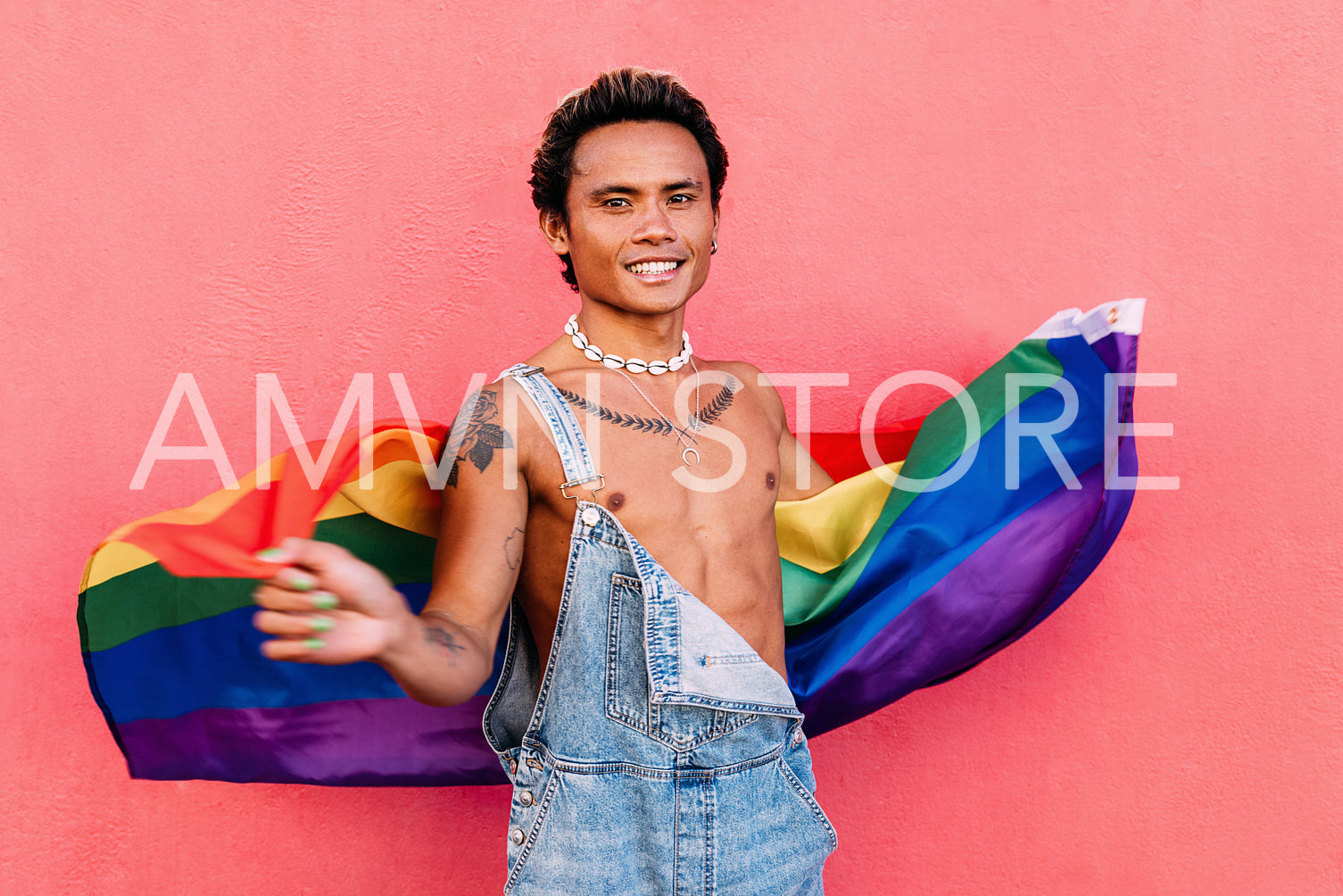 Portrait of a young happy guy with rainbow LGBT flag looking at camera