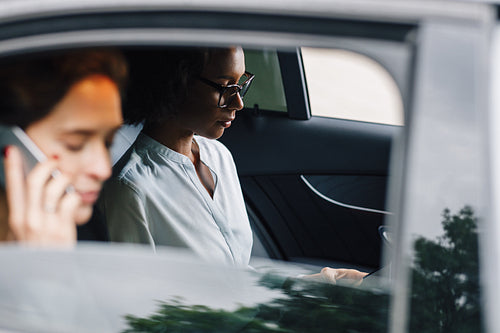 Two business colleagues working from the backseat of a taxi