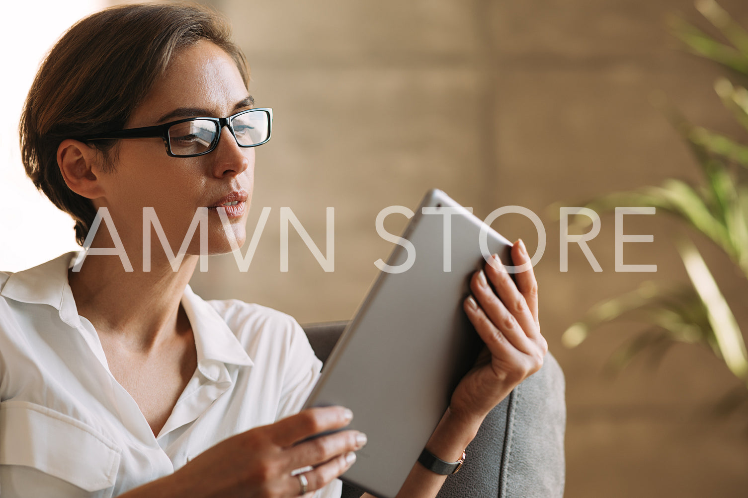 Close-up of a female with glasses and short hairstyle holding a digital tablet