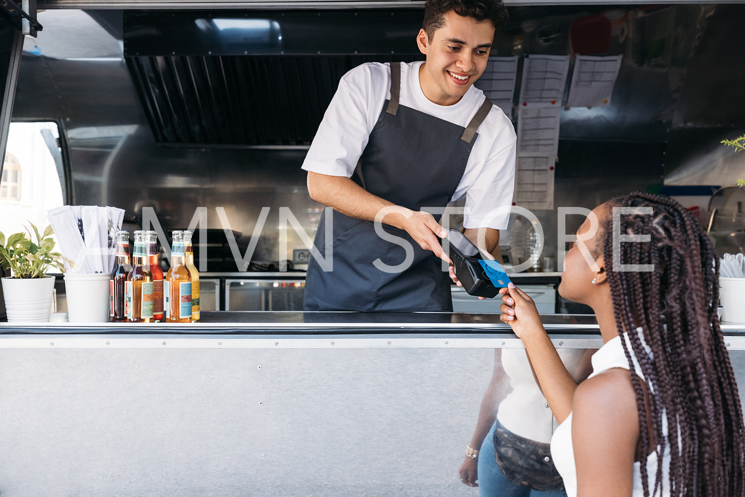 Young food truck owner receiving payment through credit card from a female customer