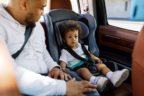 Young father and his little son fastened by belts on the backseat of a car