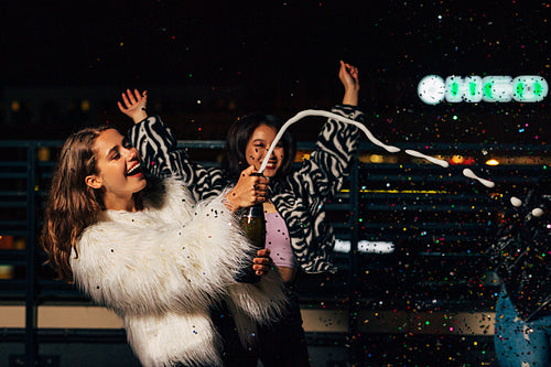 Laughing girls having fun on the roof with confetti and champagne