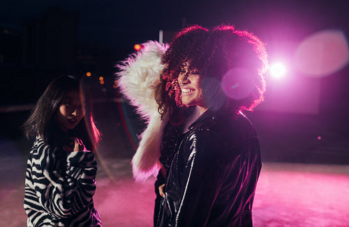 Small group of girls standing together at night near pink light