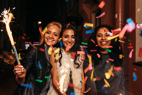 Group of friends with sparklers enjoying new years eve under confetti