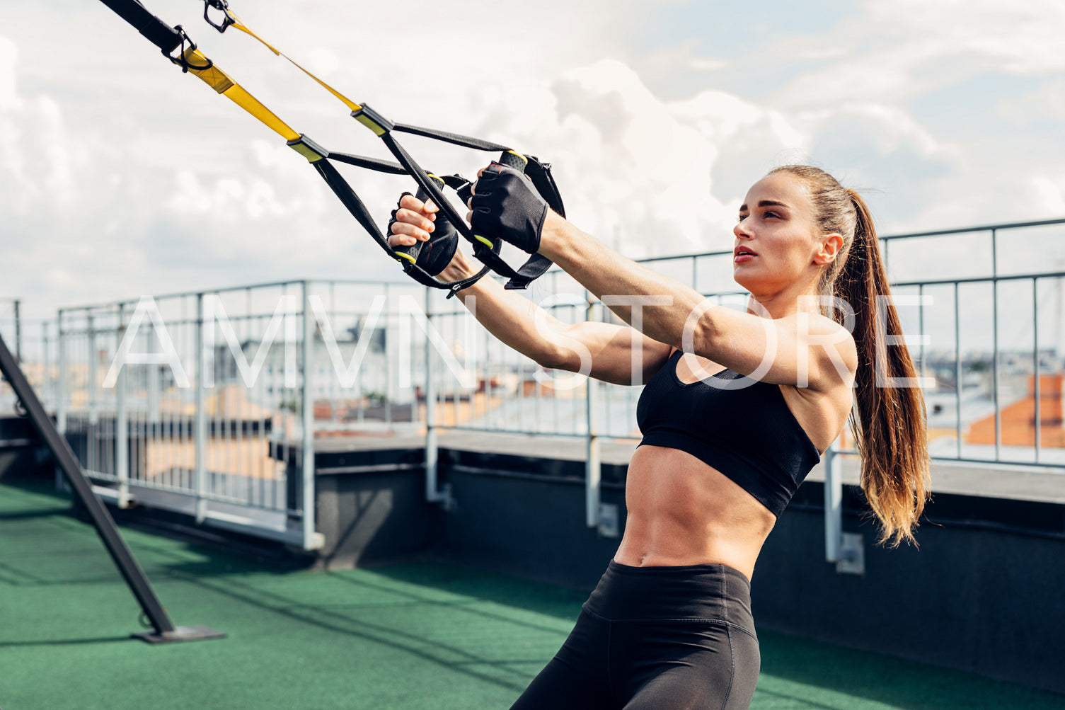 Young athlete doing push ups on a terrace. Woman exercising outdoors with suspension straps.	
