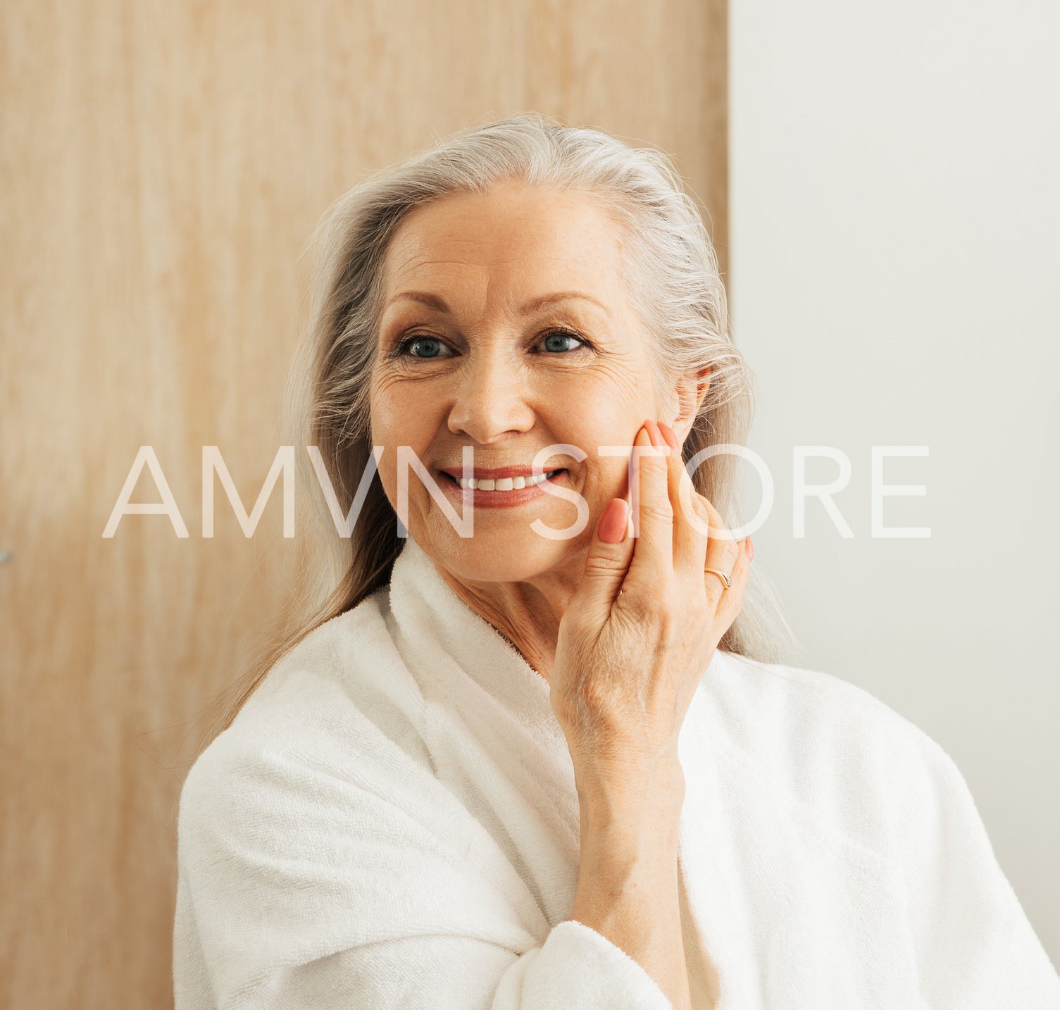 Smiling senior female touching her face with hand in front of a mirror