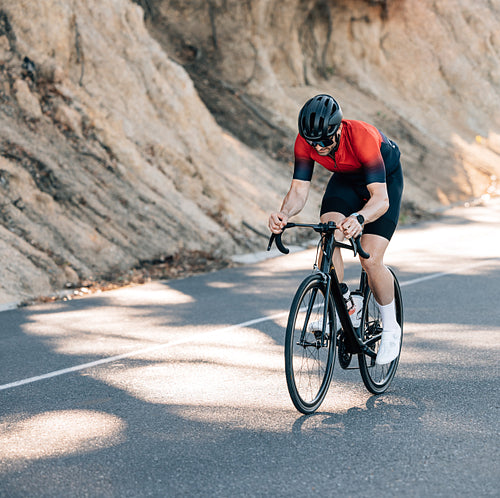 Professional cyclist in helmet and glasses riding a road bike