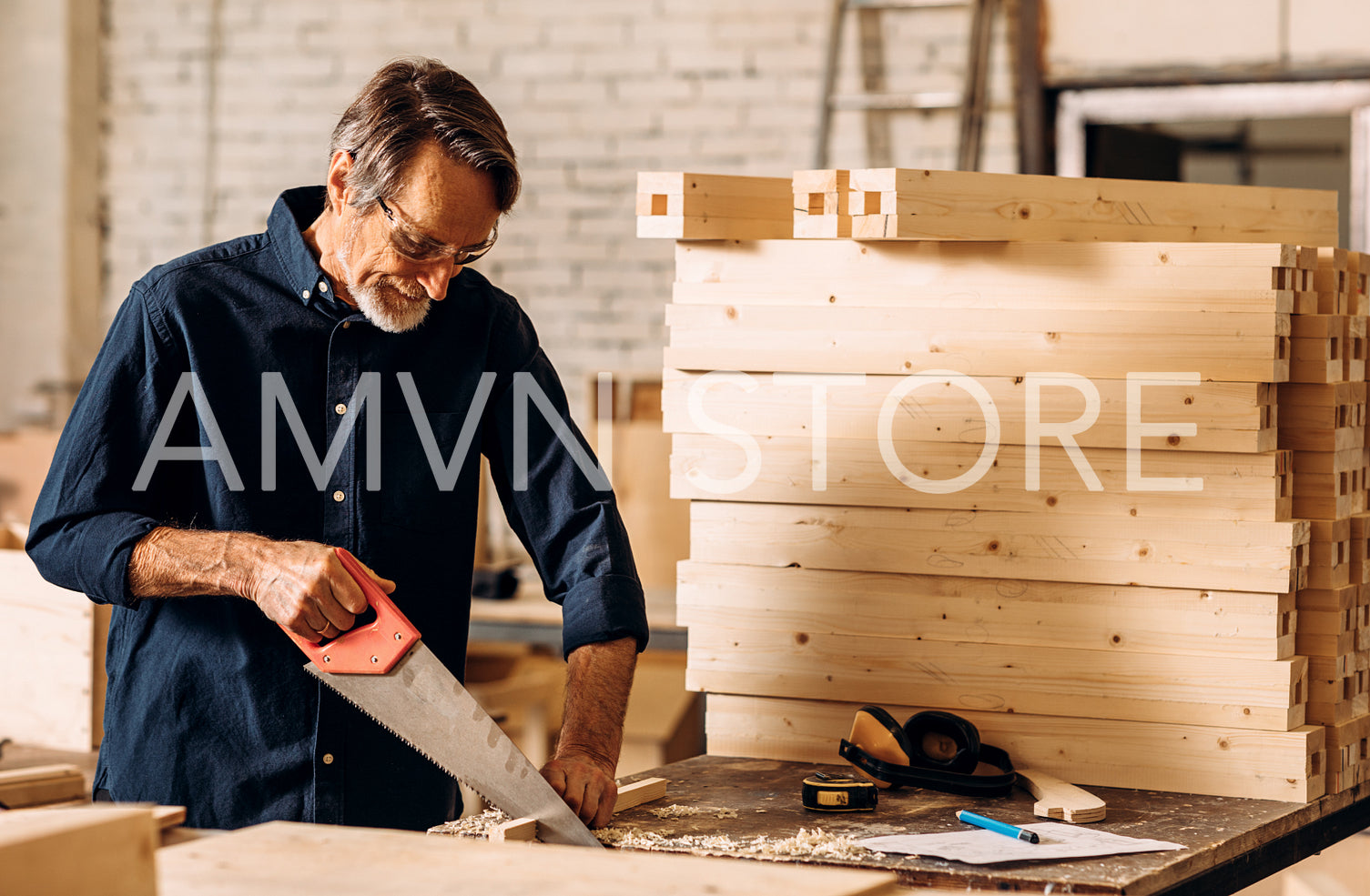 Carpenter cutting plank with hand saw in workshop	