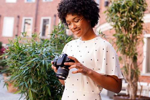 Young tourist viewing photos on digital camera while sitting outdoors