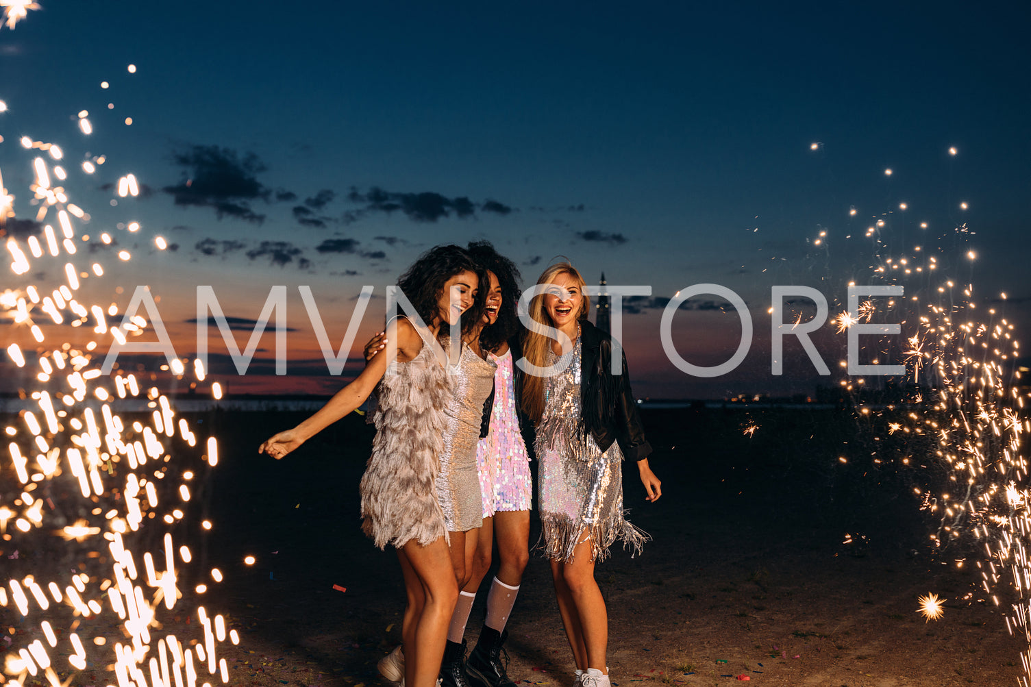 Four beautiful women standing outdoors between fireworks. Happy friends celebrating at sunset.	