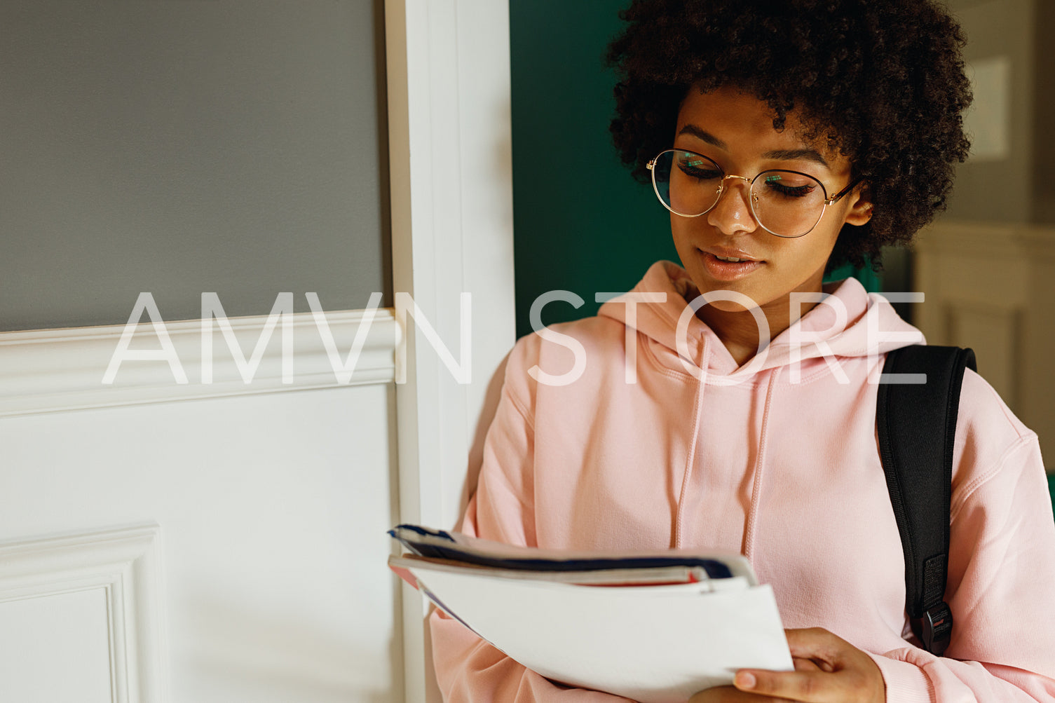 Student girl reading paper at wall indoors	